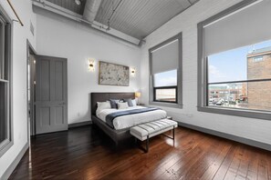 A bedroom with a bed, a bench, a window, and a painting on the wall. - Luxury 3BR on TQL Stadium & Washington Park (Cincinnati)
