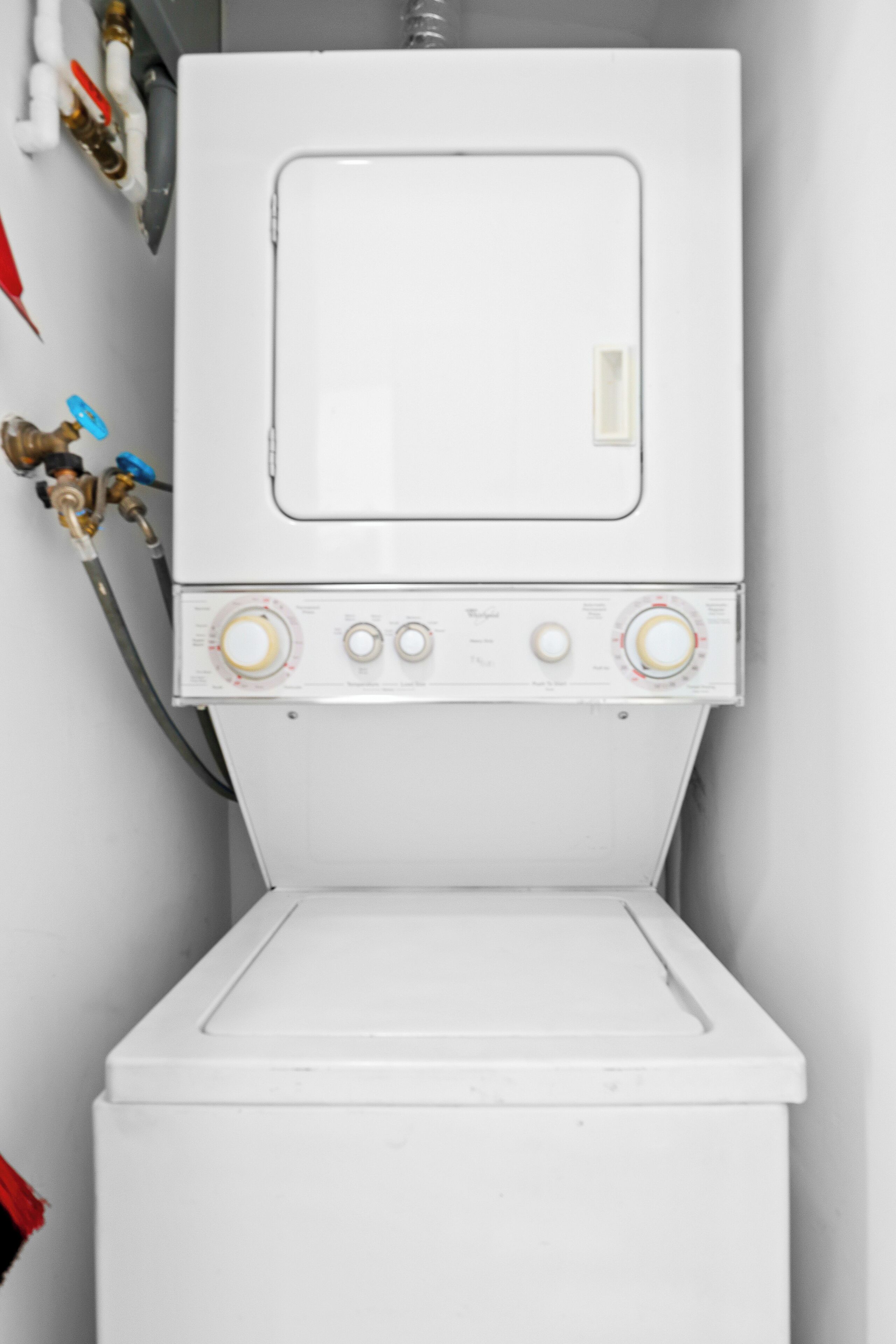A white washing machine with control knobs and hoses.