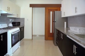 A kitchen with a stove, microwave, oven, and refrigerator. - Malecon dream, Splendid air-conditioned apartment with pool and parking (Santo Domingo Este)