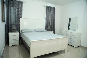 A bedroom with a bed, nightstands, a dresser, and a mirror. - Malecon dream, Splendid air-conditioned apartment with pool and parking (Santo Domingo Este)