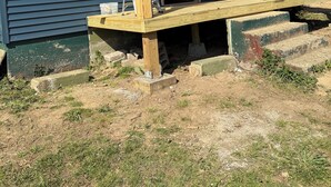 Ett hus under uppförande med en träveranda, en dörr och ett fönster.