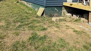 Ett envåningshus med mörkblå fasad, vita fönsterramar och en träveranda.