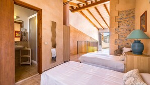 Una camera da letto con due letti, un bagno e una scala che conduce a un livello superiore.