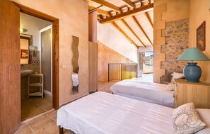 Ein Schlafzimmer mit zwei Betten, einem Badezimmer und einer Treppe, die zu einer oberen Ebene führt.