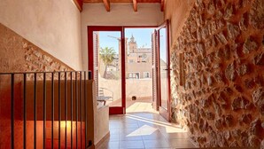 Un corridoio con parete in pietra, cancello metallico e vista sugli edifici circostanti.