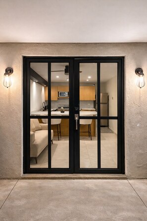 Une cuisine moderne équipée d’un four à micro-ondes, d’un réfrigérateur et d’un coin repas, le tout visible à travers une porte-fenêtre coulissante.