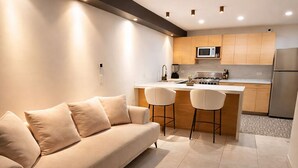 Een moderne keuken met een centraal eiland, een plafondventilator, inbouwspots en een bank met bijpassend voetenbankje.