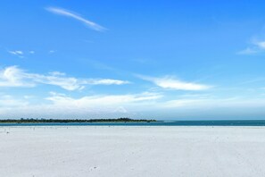 Una playa con cielo despejado y una costa lejana.