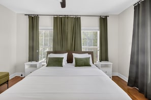 A bedroom with a large bed, two bedside tables, a nightstand, and a window with curtains. - Colorful Stylish Museum & Med District + Parking (Houston)