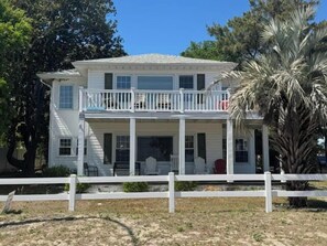 A two-story house with a balcony, a covered porch, and a fenced yard. - Sand in our Shoes | Coastal comfort just steps from the shore 🌊 (North Myrtle Beach)
