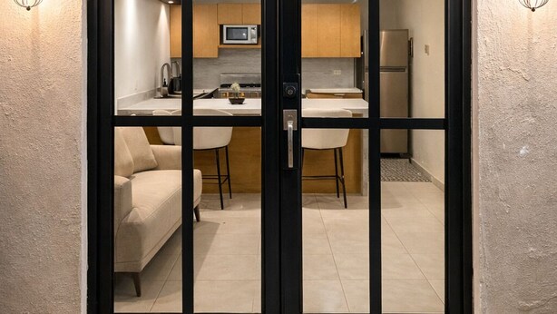 Cozinha moderna com micro-ondas, frigorífico e zona de refeições visíveis através de uma porta de correr de vidro.