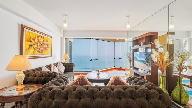 Ein Wohnzimmer mit Meerblick, einer Couch, einem Couchtisch und einem Bücherregal.