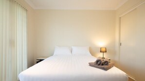 Une chambre d’hôtel avec un grand lit, une table de chevet avec une lampe et une paire de serviettes posées sur le lit.