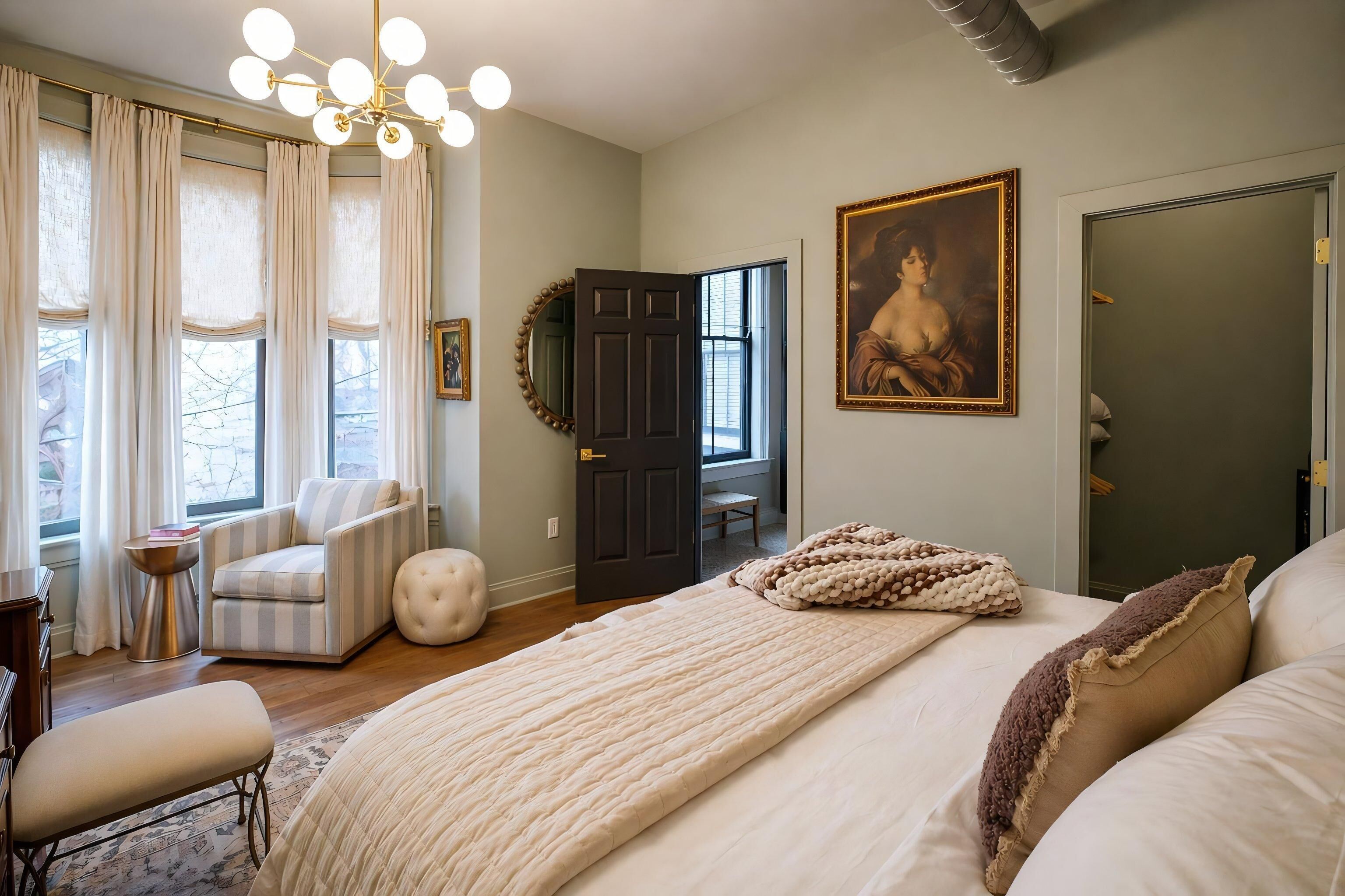 Un dormitorio con una cama grande, una silla, un escritorio y una puerta.
