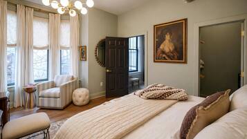 Un dormitorio con una cama grande, una silla, un escritorio y una puerta.