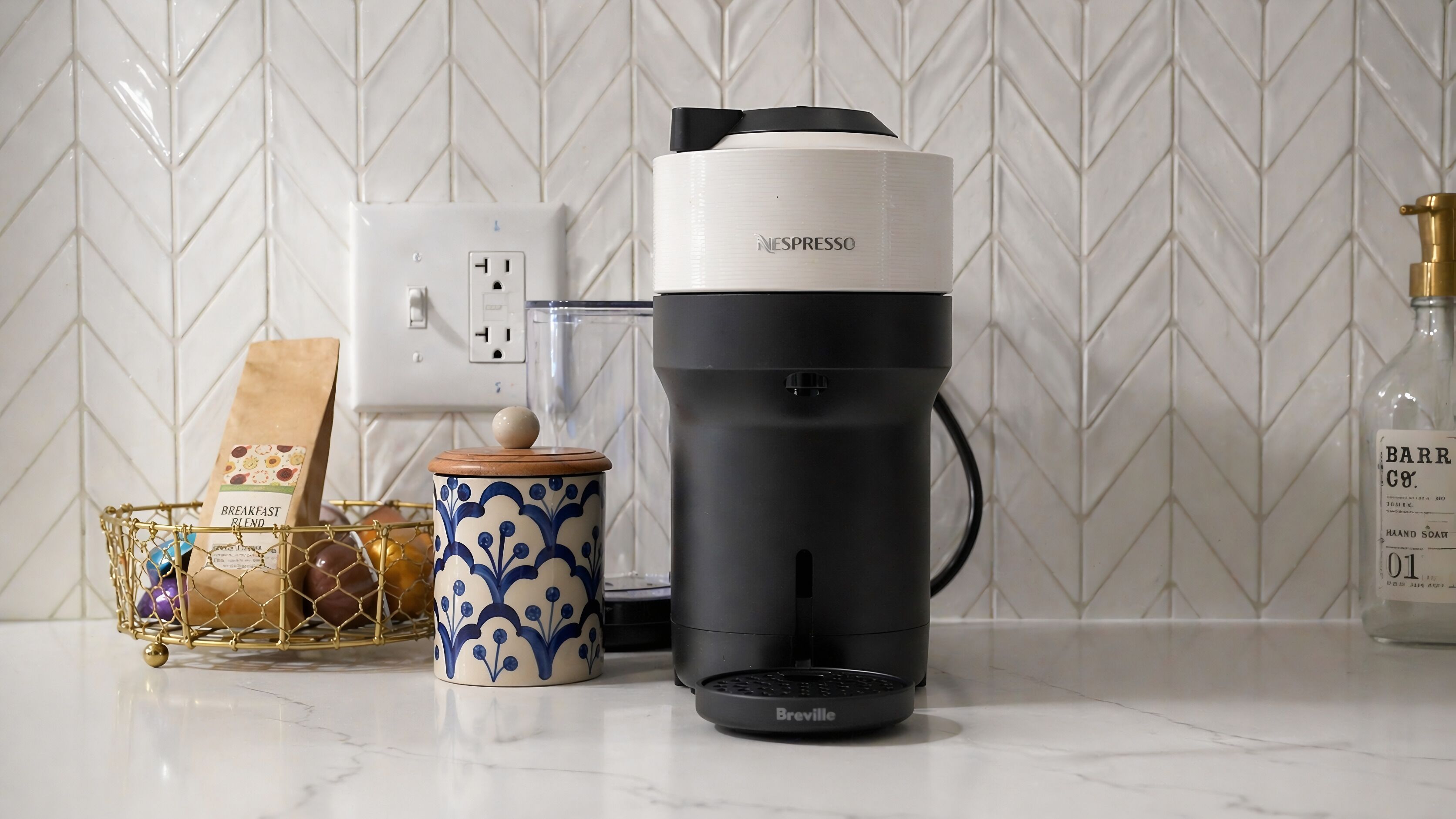 A kitchen with a Nespresso coffee machine, a Breville coffee maker, a coffee grinder, and a bottle of hand soap.
