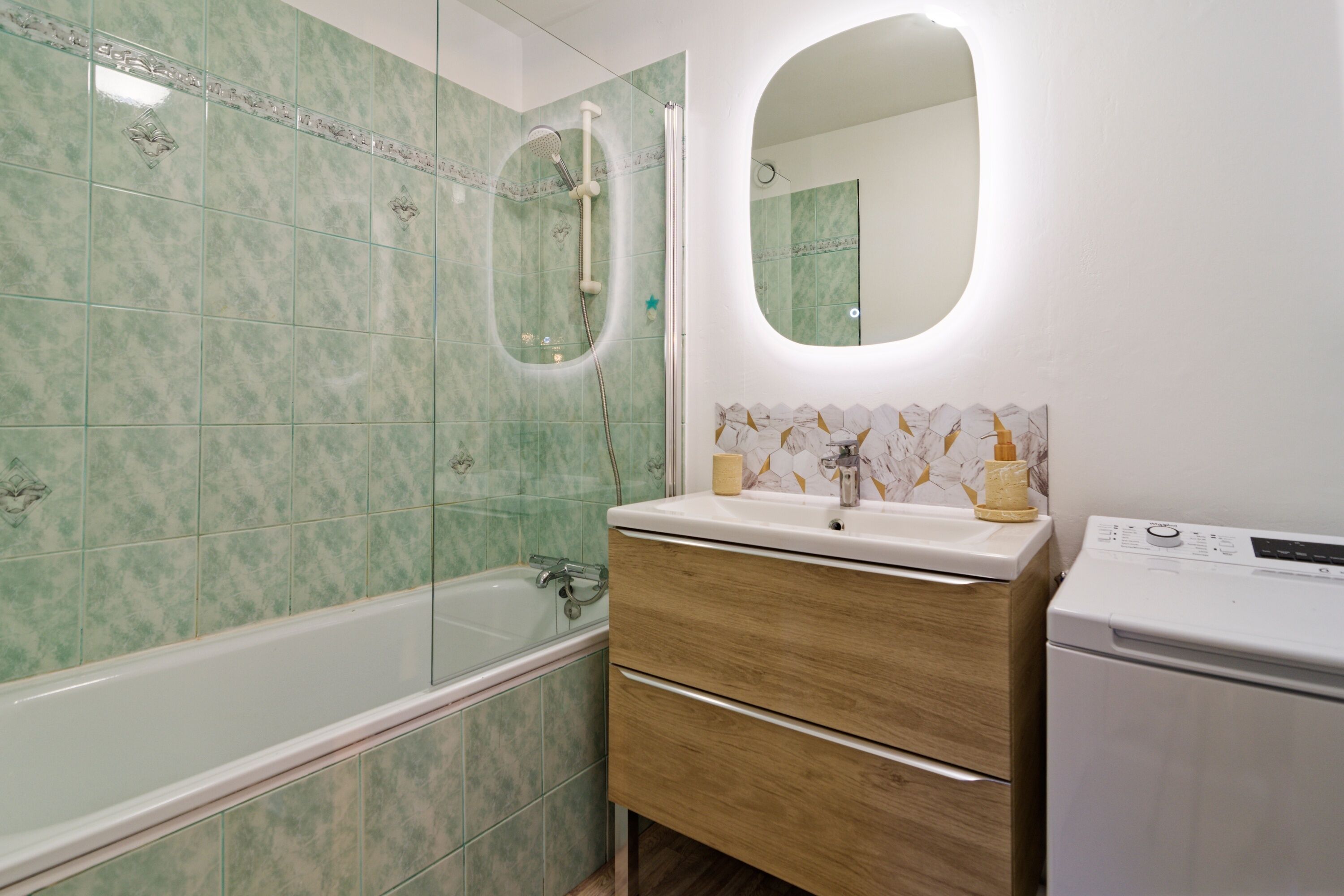 A bathroom with a bathtub, a vanity with a mirror, and a washing machine.