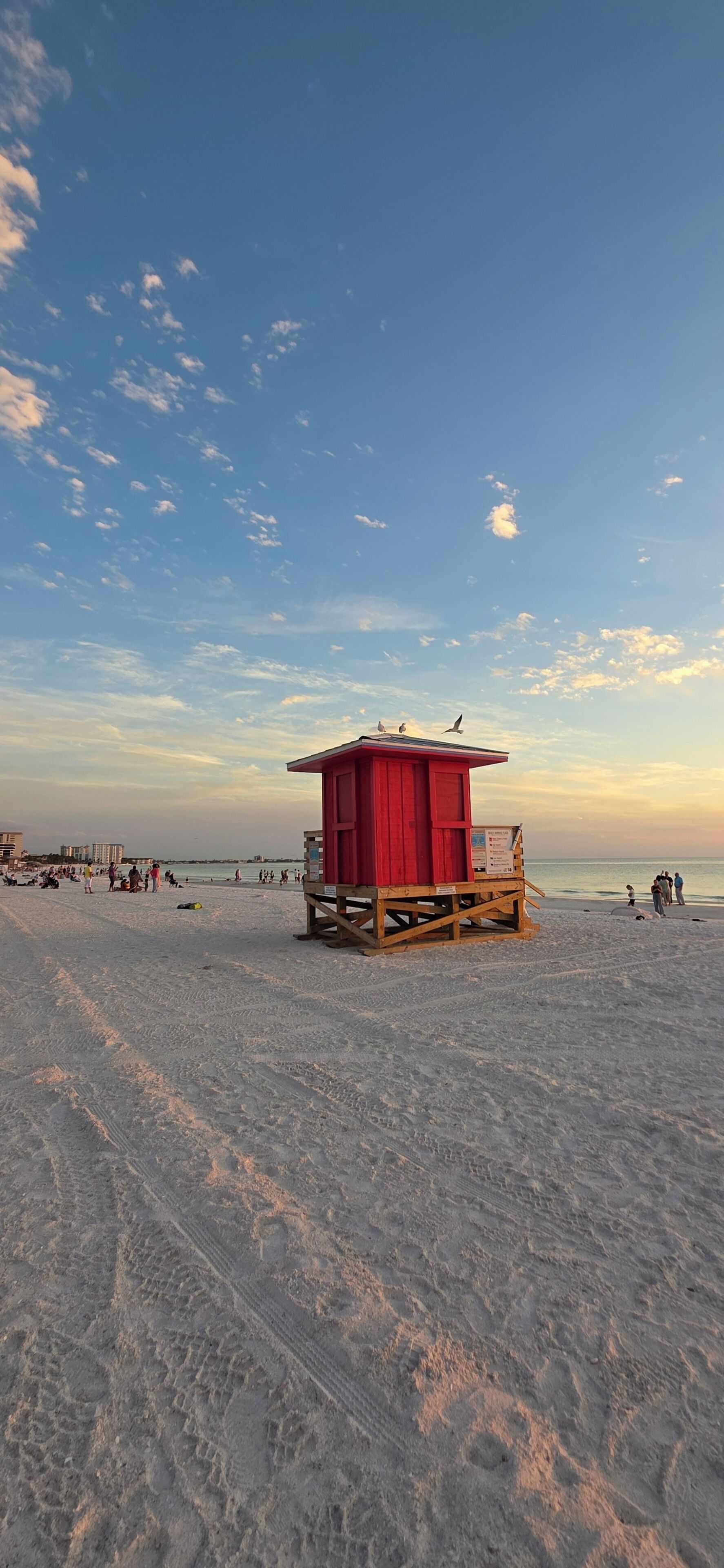 Una playa con una torre de salvavidas, arena y el océano al fondo.