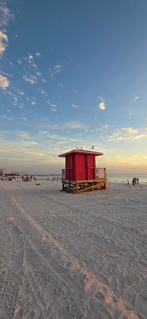 En strand med en livredderstand og sand, samt hav i baggrunden.