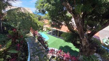 Um jardim exuberante com piscina, caminho de pedra e um gazebo.