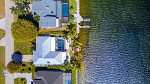 En bostadsfastighet med en swimmingpool, en täckt uteplats och utsikt över en sjö.