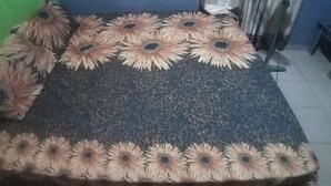 Una cama con colcha y almohadas estampadas con motivos florales.