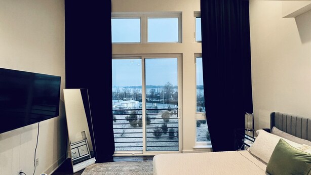 Une chambre d’hôtel moderne dotée d’un grand lit, d’un téléviseur à écran plat, d’un canapé et offrant une vue sur l’extérieur grâce à une grande fenêtre.