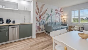 A modern kitchen with a dishwasher, coffee maker, and a dining area with a white table and chairs. - Comfy suite near Epic and Universal - free parking (Orlando)