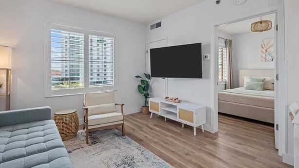 A modern living room with a sofa, TV, and a bed in the adjacent room. - Comfy suite near Epic and Universal - free parking (Orlando)