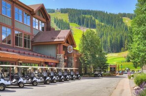 A lodge with a large building, a parking area with golf carts, and a mountainous backdrop. - New Listing! Stylish new design, ski in/out. Watch World Cup, view golf course! (Frisco)