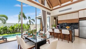 Cozinha moderna com uma ilha grande, banquetas e vista para uma piscina.
