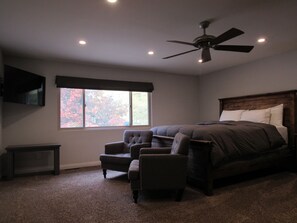A bedroom with a bed, a chair, a ceiling fan, a window, and a TV on the wall. - 3 Bedroom, 2 Bath w/Spa & Gameroom, Walk to Park & Lake 1/2 mile to Ski/Shopping (Big Bear Lake)