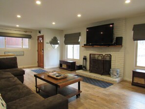 A living room with a fireplace, a television, and a sofa. - 3 Bedroom, 2 Bath w/Spa & Gameroom, Walk to Park & Lake 1/2 mile to Ski/Shopping (Big Bear Lake)