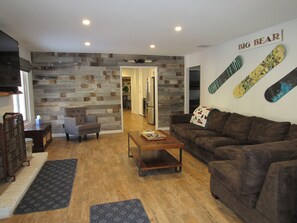 A modern living room with a brown sofa, a wooden coffee table, and a patterned rug. - 3 Bedroom, 2 Bath w/Spa & Gameroom, Walk to Park & Lake 1/2 mile to Ski/Shopping (Big Bear Lake)