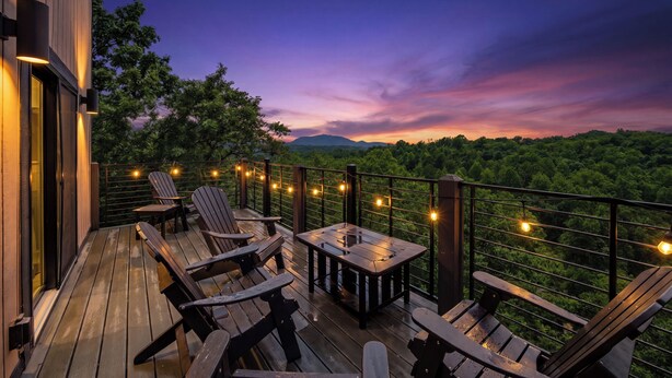 Eine Holzdar Terrasse mit Stühlen und einem Tisch, mit Blick auf eine bewaldete Landschaft.