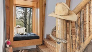 A wooden staircase with a rustic design, a window seat with a cushion, and a cowboy hat on the railing. - Abode at Luxe Barnhouse, teton views, hot tub (Jackson)