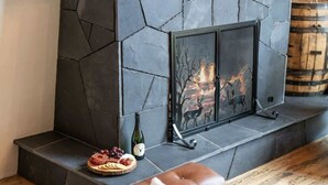 A fireplace with a stone mantle, a bottle of wine, and a plate of food on the mantel. - Abode at Luxe Barnhouse, teton views, hot tub (Jackson)