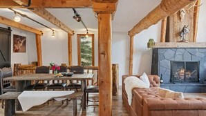 A rustic interior with exposed wooden beams, a fireplace, a dining area, and a leather sofa. - Abode at Luxe Barnhouse, teton views, hot tub (Jackson)