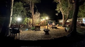 A nighttime outdoor area with a gazebo, seating, and a fire pit. - Froggy`s Quarters Cabin 1 - Cockatoo (Halls Gap)