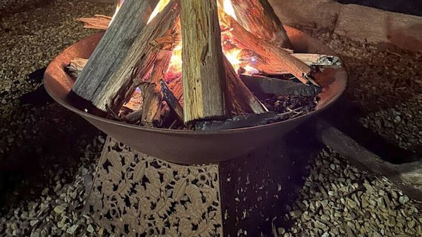 A fire pit with logs, surrounded by gravel, with a building and stairs in the background. - Froggy’s Quarters Cabin 3 - Emu (Halls Gap)