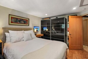 Ein Hotelzimmer mit einem großen Bett, einem Fernseher, einem Kleiderschrank und einem Bild an der Wand.