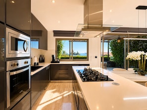 A modern kitchen with a large island, built-in appliances, and a view to the outdoors. - Casa Vista 133 · Private Luxury Villa w/ Rooftop Views in Cabo (Cabo San Lucas)
