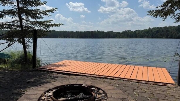 Une terrasse au bord du lac, avec un foyer et une plateforme en bois qui s’étend sur l’eau.