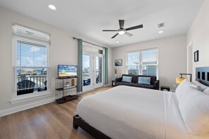 A hotel room with a large bed, a ceiling fan, a TV, and a balcony with a city view. - Dog Friendly Beach House 200ft from the Beach (Gulf Shores)