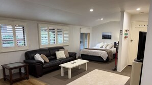 A compact living space with a sofa, a small table, a bed, and a television.