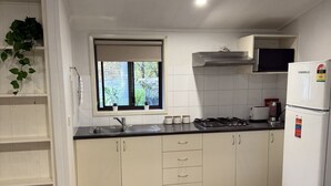 A modern kitchen with white cabinets, a built-in stove, a sink, and a window.
