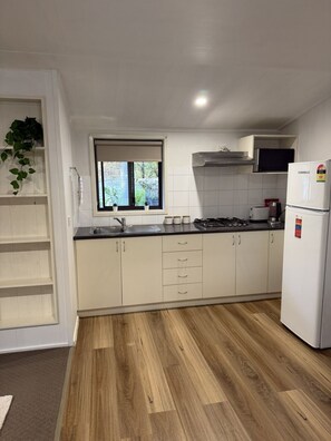 Una cocina moderna con armarios blancos, estufa integrada, un lavabo y un ventanal.