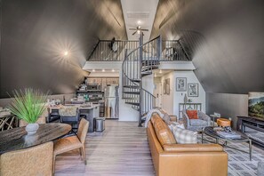 Ein großzügiger Wohnbereich mit Treppe zu einer oberen Ebene, ein Essbereich mit Tisch und Stühlen sowie eine Küche im Hintergrund.