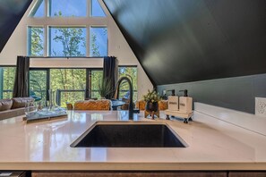 Eine moderne Küche mit einem großen Fenster, einer Spüle und einer Arbeitsfläche mit einer Seifenspenderflasche.