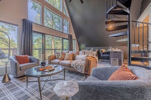 Ein modernes Wohnzimmer mit Sofa, Sessel, Couchtisch und einer Wendeltreppe.
